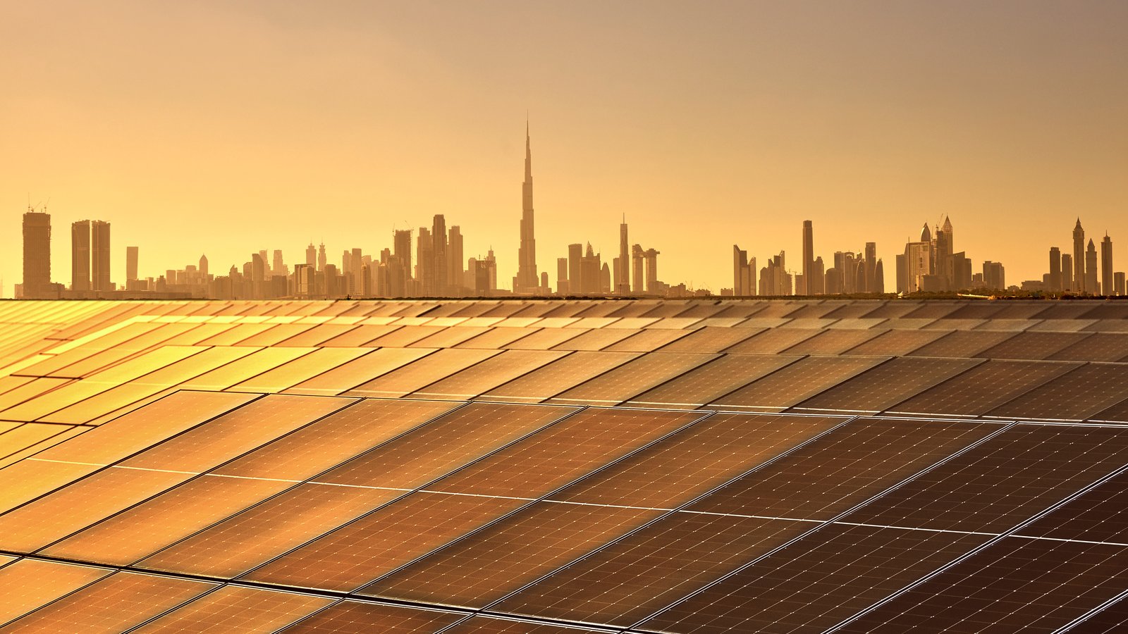 Solar panels with Dubai skyline and Burj Khalifa at sunset