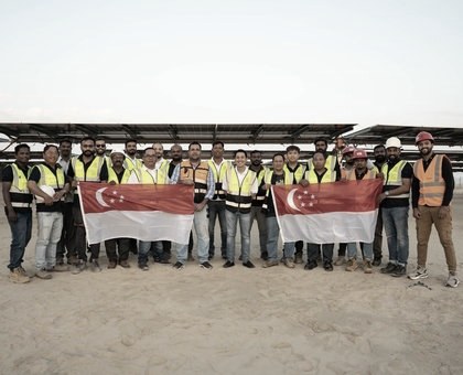 SME team celebrating a solar site milestone with the Singapore flag