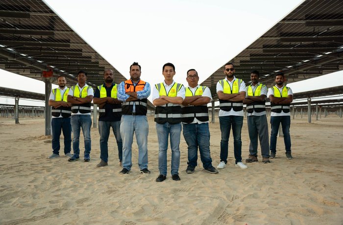 SME site team standing under the solar array